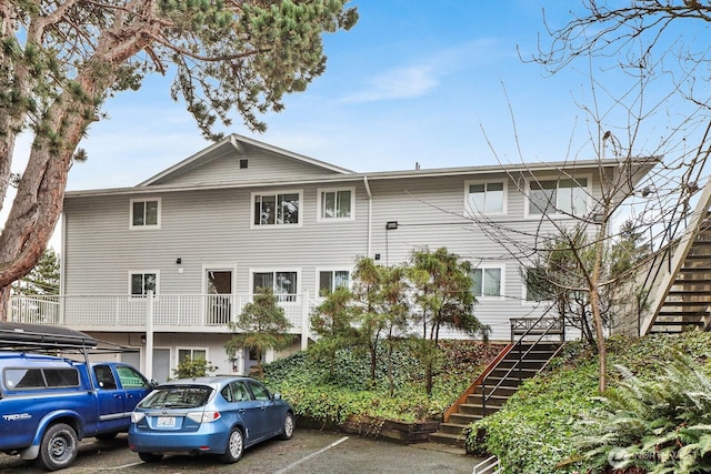 view of property with uncovered parking and stairs