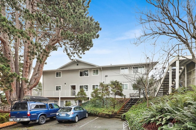 view of building exterior featuring stairway and uncovered parking