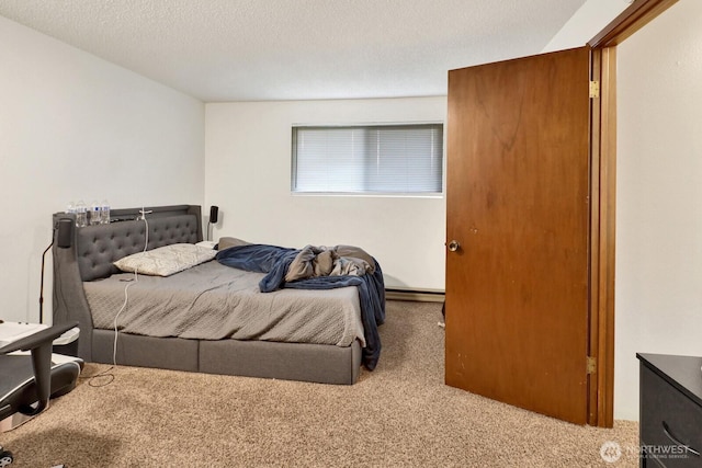 carpeted bedroom featuring baseboard heating and a textured ceiling