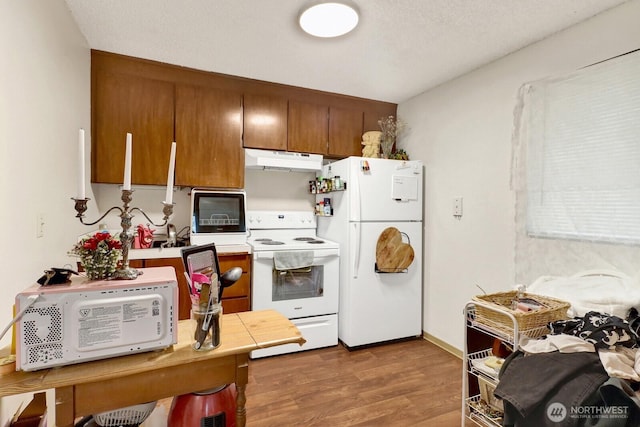 kitchen with white appliances, wood finished floors, light countertops, under cabinet range hood, and brown cabinets