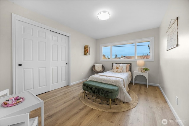 bedroom with a closet, baseboards, and light wood-style flooring