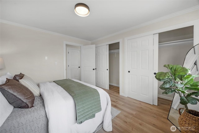 bedroom with light wood-style flooring, two closets, crown molding, and baseboards