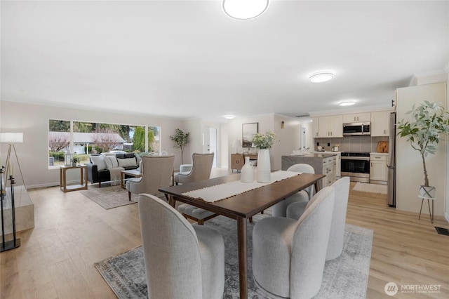 dining space with visible vents, light wood-type flooring, and baseboards