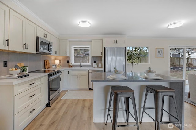 kitchen featuring crown molding, a breakfast bar area, appliances with stainless steel finishes, and a sink