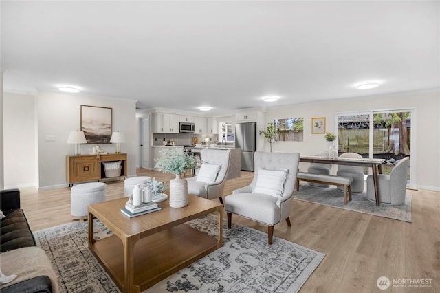 living area with light wood-type flooring, baseboards, and ornamental molding