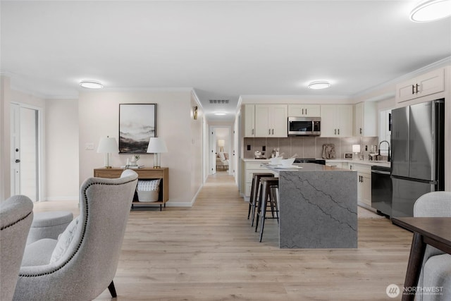 kitchen featuring ornamental molding, visible vents, backsplash, and stainless steel appliances