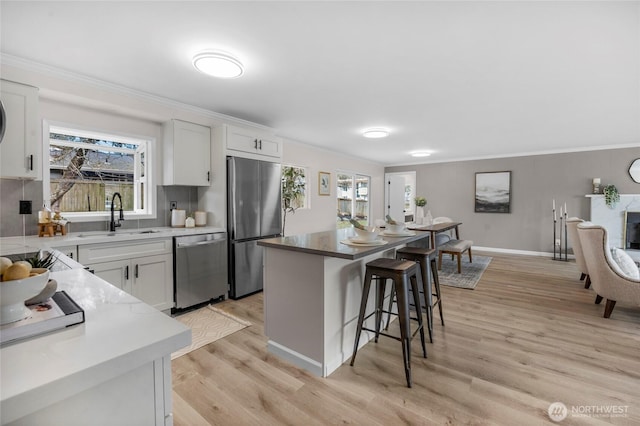 kitchen with a sink, appliances with stainless steel finishes, a breakfast bar area, and ornamental molding