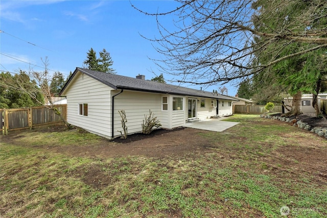 rear view of house featuring a patio area, a yard, a fenced backyard, and a chimney