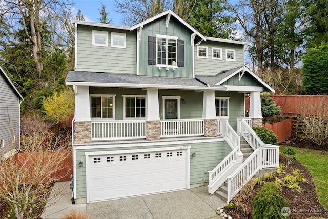 craftsman house featuring fence, a porch, a garage, stone siding, and board and batten siding