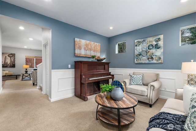 living area featuring recessed lighting, a wainscoted wall, and light carpet