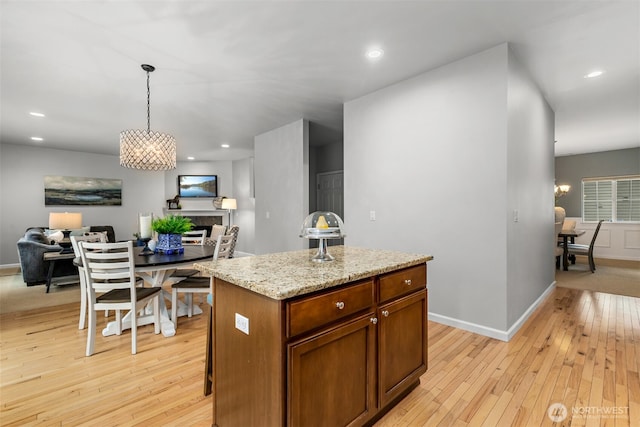 kitchen with a center island, open floor plan, light wood-style flooring, recessed lighting, and hanging light fixtures