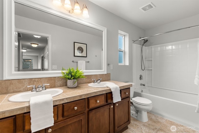 bathroom featuring visible vents, toilet, double vanity, a sink, and tub / shower combination