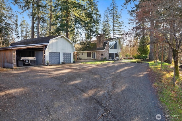 view of front of home featuring an outdoor structure, a garage, and a gambrel roof