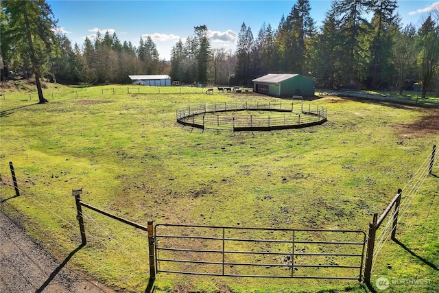 view of yard featuring a view of trees, an outdoor structure, a pole building, and fence