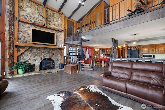 living room with beam ceiling, high vaulted ceiling, wood finished floors, stairway, and a wood stove