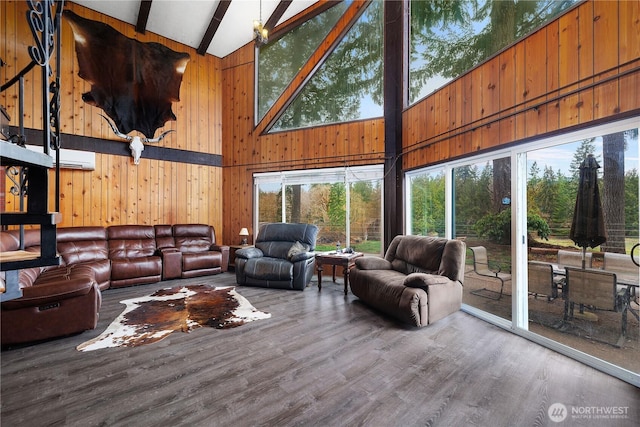 living room with wood finished floors, beam ceiling, plenty of natural light, and wood walls