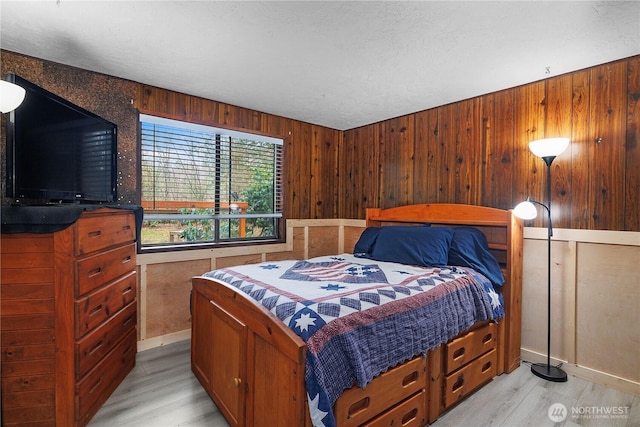 bedroom with light wood-style floors and wood walls