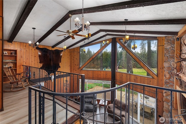 interior space with vaulted ceiling with beams, wood finished floors, wood walls, and a chandelier