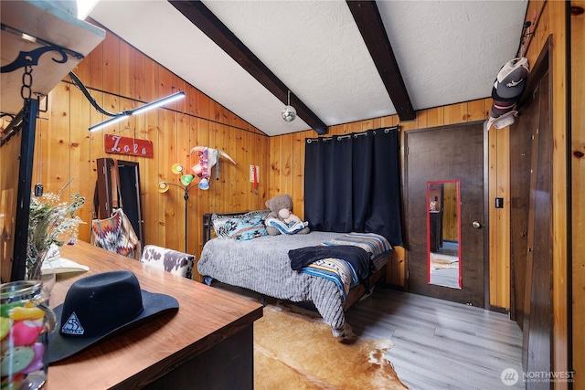 bedroom with light wood-style flooring, vaulted ceiling with beams, wood walls, and a textured ceiling