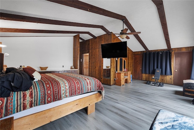 bedroom featuring lofted ceiling with beams, wooden walls, and wood finished floors