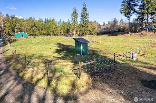 view of yard featuring a rural view, an outbuilding, and fence