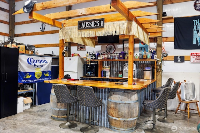 bar with freestanding refrigerator, unfinished concrete floors, and a dry bar