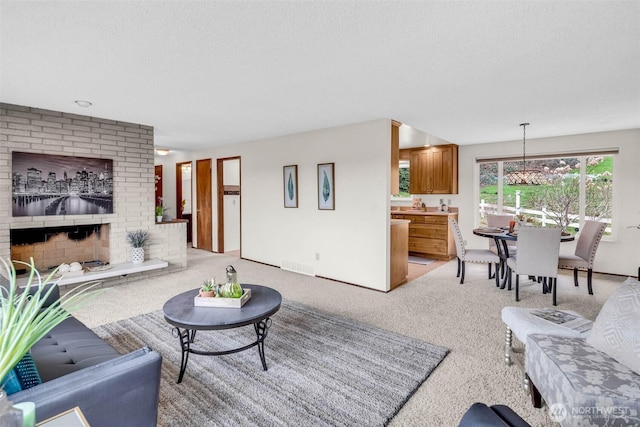 living room featuring a textured ceiling, a brick fireplace, visible vents, and light carpet