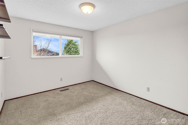 empty room featuring visible vents, baseboards, a textured ceiling, and carpet flooring