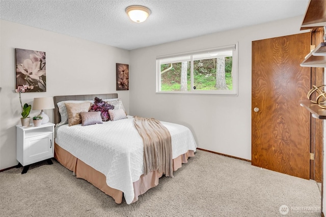 bedroom with light colored carpet, a textured ceiling, and baseboards