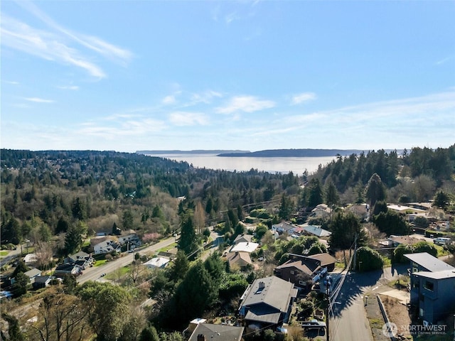 birds eye view of property featuring a water view and a wooded view