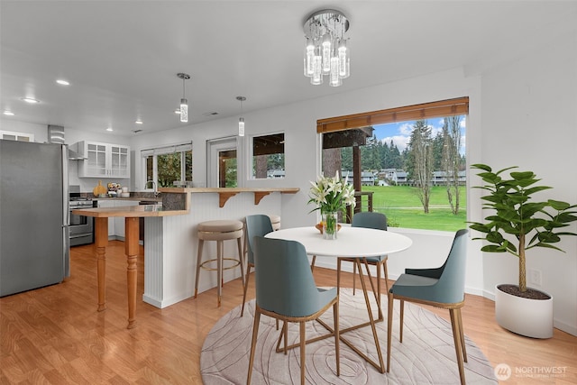 dining room with a notable chandelier, light wood-style floors, recessed lighting, and a healthy amount of sunlight