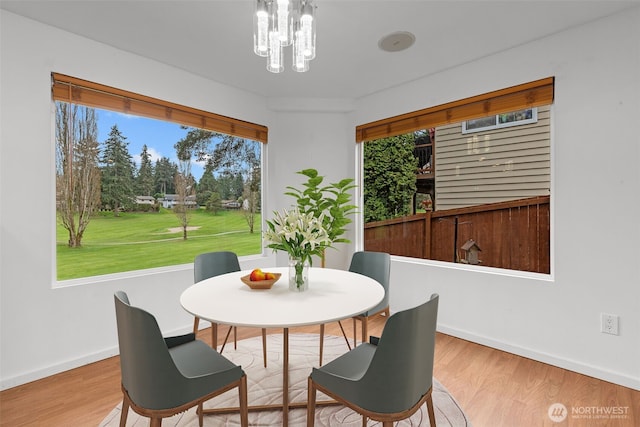 dining area featuring a chandelier, baseboards, and wood finished floors