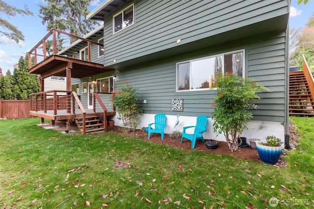 rear view of property featuring a yard, a wooden deck, and stairs