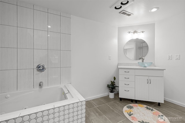 bathroom featuring vanity, baseboards, visible vents, a whirlpool tub, and tile patterned floors