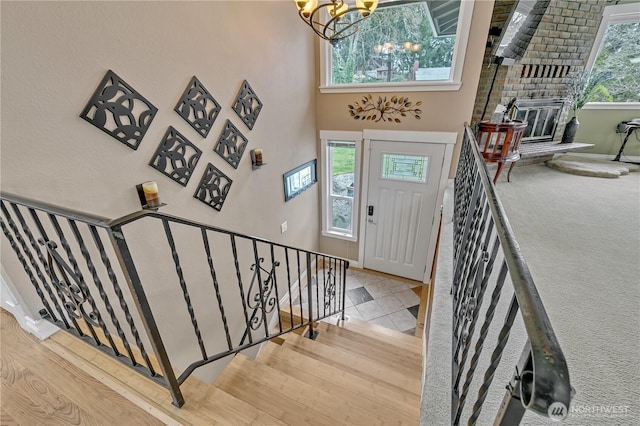 foyer entrance featuring a notable chandelier, a fireplace, stairway, and a towering ceiling