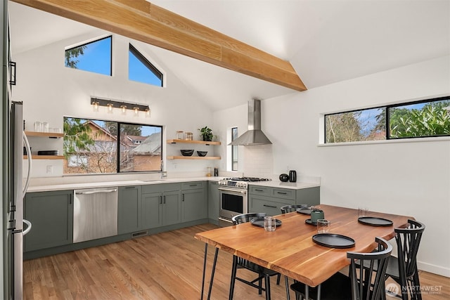 dining room featuring beam ceiling, light wood-style flooring, and a healthy amount of sunlight