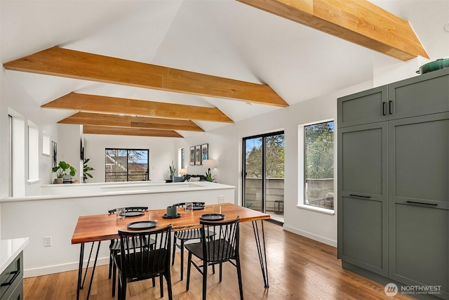 dining area featuring lofted ceiling with beams, wood finished floors, and baseboards