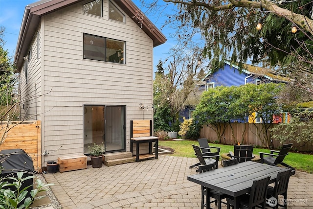 rear view of property featuring fence, a lawn, entry steps, and a patio area