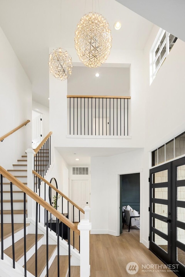 staircase with visible vents, a high ceiling, wood finished floors, and french doors