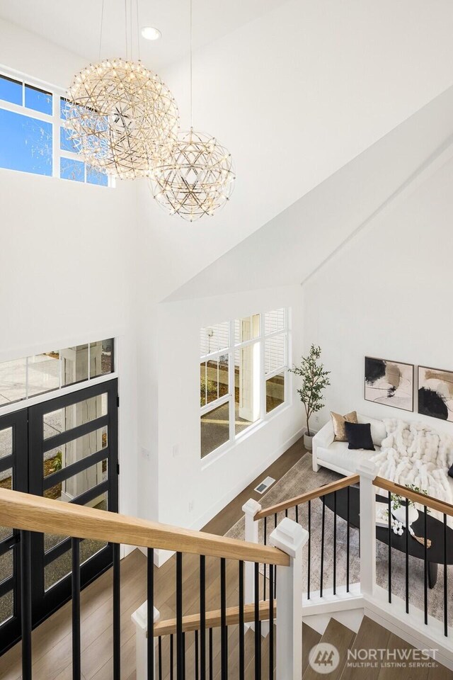 staircase with wood finished floors, visible vents, recessed lighting, a towering ceiling, and a notable chandelier