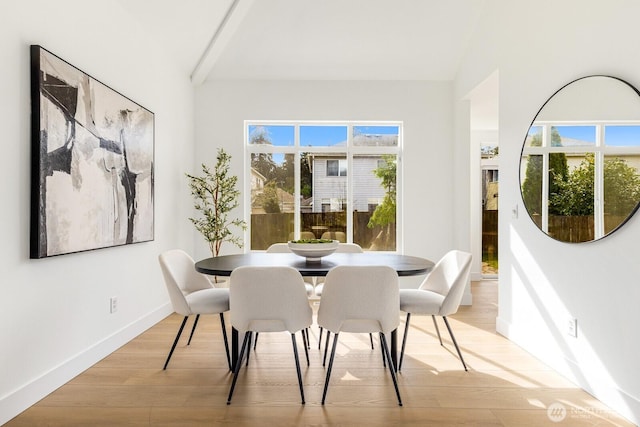 dining area featuring vaulted ceiling, light wood-style floors, and baseboards