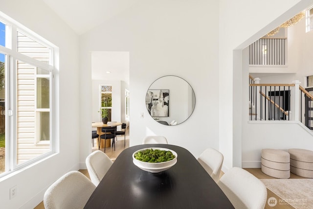 dining space with baseboards, stairs, and vaulted ceiling