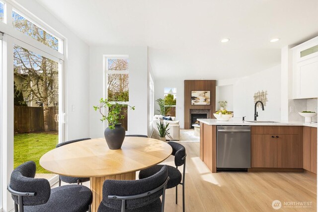 kitchen with recessed lighting, a sink, light countertops, light wood-style floors, and stainless steel dishwasher