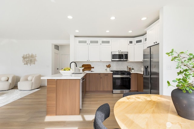 kitchen with stainless steel appliances, backsplash, a peninsula, and light countertops