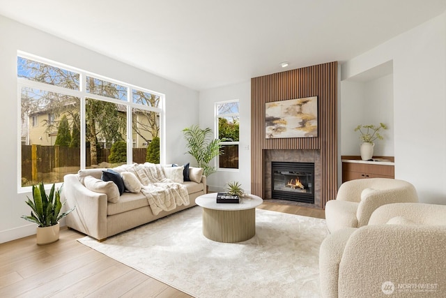 living room with a tiled fireplace and light wood-style floors