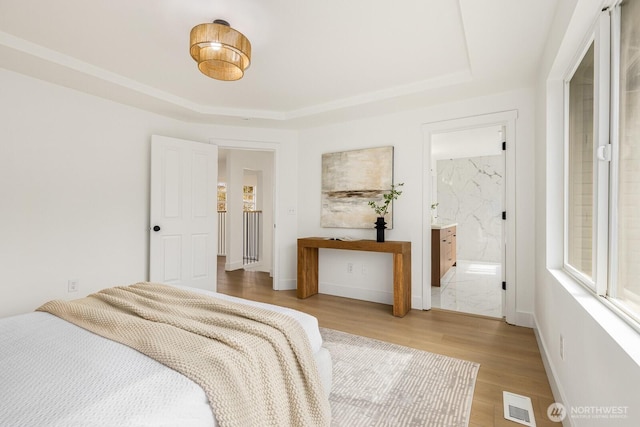 bedroom featuring visible vents, a raised ceiling, baseboards, and wood finished floors