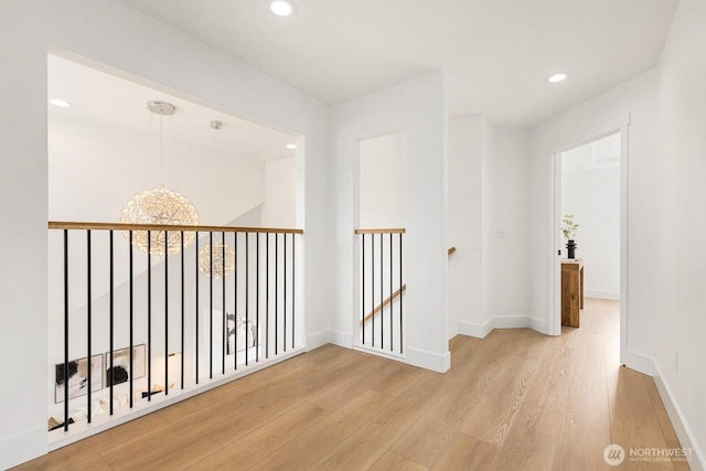 corridor with an upstairs landing, light wood-style floors, recessed lighting, and baseboards