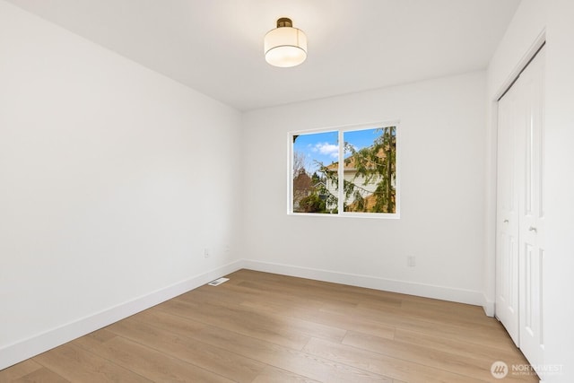 unfurnished bedroom featuring light wood-style flooring, visible vents, baseboards, and a closet