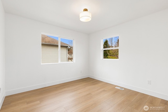 unfurnished room featuring light wood-type flooring, plenty of natural light, and baseboards