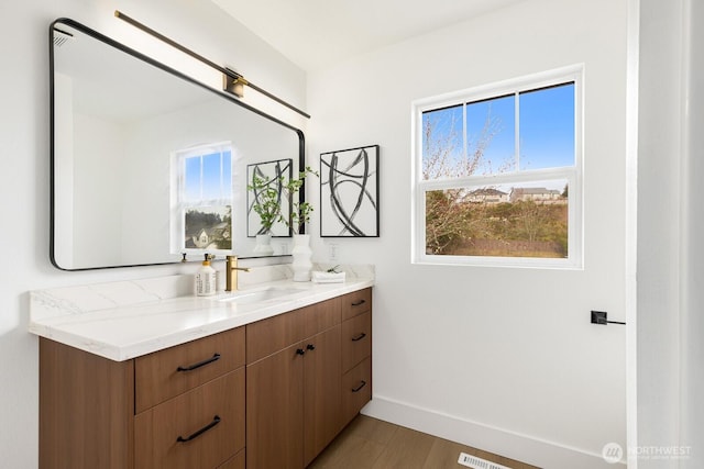 bathroom featuring vanity, wood finished floors, and baseboards